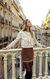 a lady in a white knitted jacket and a Khaki half skirt